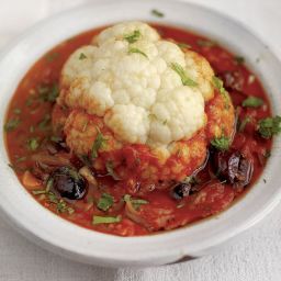 Whole baked cauliflower with tomato and olive sauce
