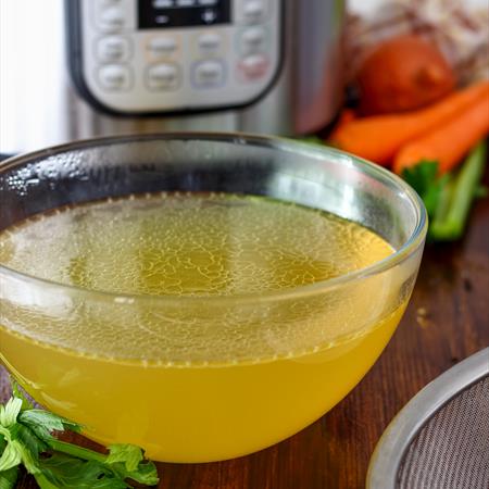 pressure cooker on countertop with chicken broth in front