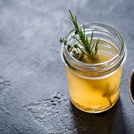 fresh bone broth in a clear jar on a dark background