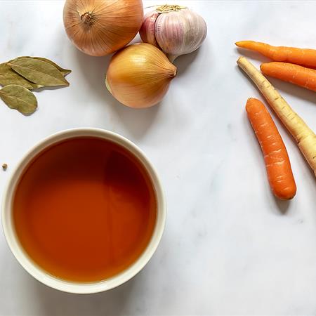 flat lay of homemade beef bone broth in a bowl with ingredients