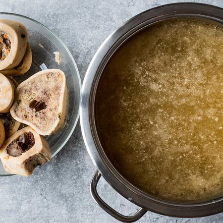 overhead of bones used for beef bone broth and bone broth bouillon in a metal pan on countertop