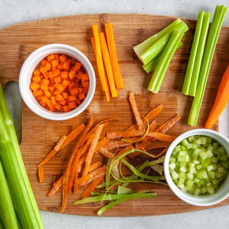 top down view of wooden cutting board with chopped carrots and celery
