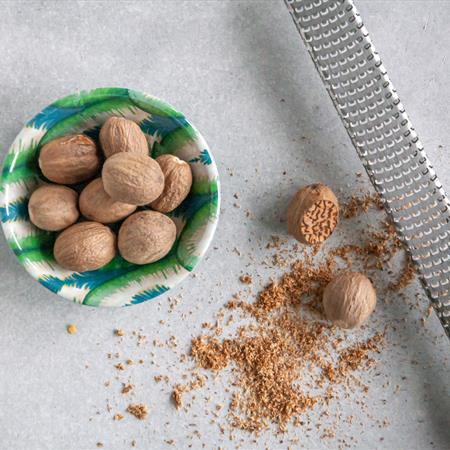 top down view of nutmeg being grated with metal grater 