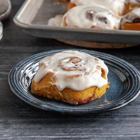 pumpkin cinnamon roll on plate with icing on top