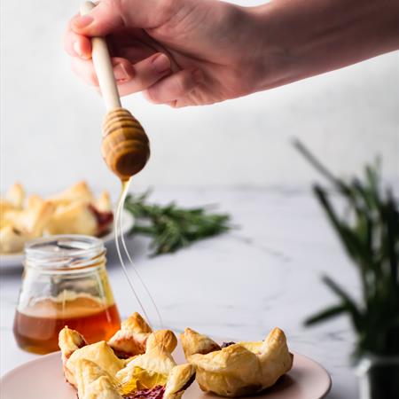 dripping honey on top of the baked cranberry brie bites from the side