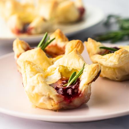 finished baked cranberry honey brie bites on a plate with a white background