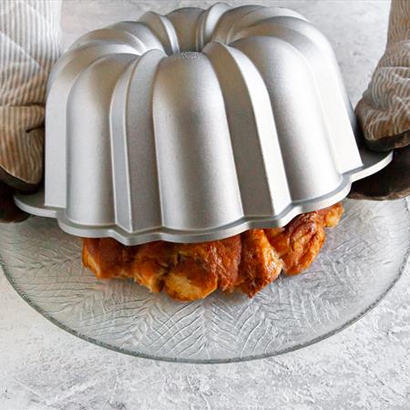 donut monkey bread in bundt pan being flip over on to plate from side view