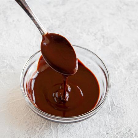 spoon in chocolate sauce on a white countertop