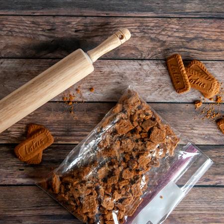 biscoff cookies in a bag with rolling pin to crumble on wooden background