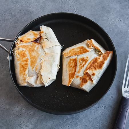 thanksgiving crunchwrap supreme being heated in pan from overhead
