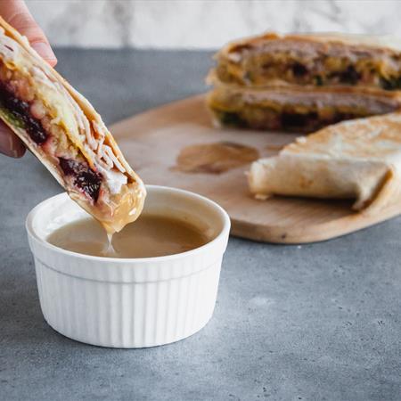 thanksgiving crunchwrap being dipped in gravy